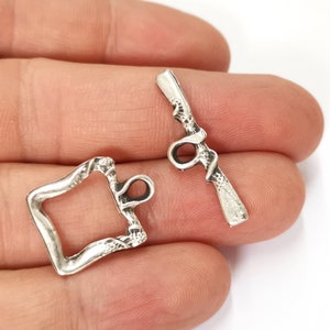 Puede incluir: Dos cierres de palanca de metal plateados con un diseño ornamentado. Los cierres están diseñados para ser utilizados en la elaboración de joyas u otros proyectos de artesanía.