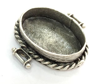 May include: Silver oval pendant setting with a rope-like border and a hinged clasp.