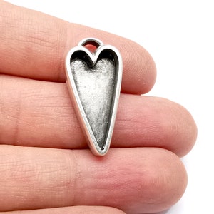 May include: Silver-toned metal heart-shaped pendant with an open center. The pendant has a slightly distressed finish.