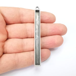 May include: Silver pendant with a rectangular frame, perfect for adding a personalized touch to jewelry projects.