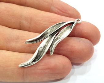 May include: Silver-toned metal pendant featuring a stylized design of three leaves. The leaves are arranged in a flowing, organic shape, with the top leaf slightly overlapping the two lower leaves.