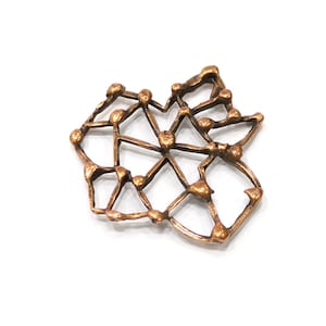 May include: A copper-colored metal pendant with a geometric design. The pendant is shaped like a star with a web-like pattern.
