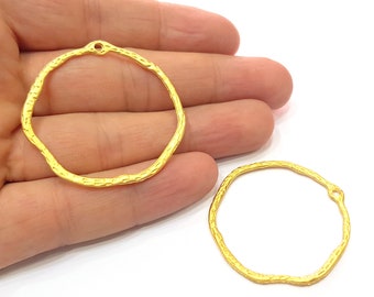 May include: Two gold-toned metal hoops with a textured surface. The hoops have a small hole at the top for attaching to jewelry.