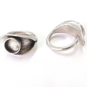 Puede incluir: Dos anillos de plata con un diseño abstracto único. Un anillo tiene una abertura circular, mientras que el otro es una banda continua.