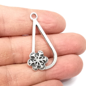 May include: Silver charm in the shape of a teardrop with a snowflake design in the center.
