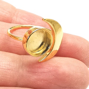 May include: Gold ring featuring a crescent moon design and a round bezel setting. The ring is adjustable and can be worn on any finger.
