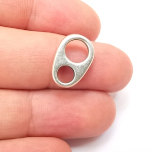 May include: Silver-toned metal connector with two oval-shaped holes. The connector is designed for attaching jewellery or other crafts.
