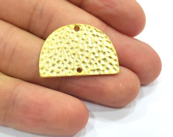 May include: A gold-coloured metal half-circle charm with a hammered texture and two holes.