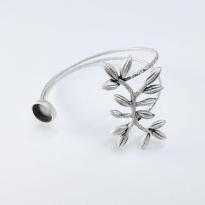 May include: Silver bracelet with a delicate leaf design. The bracelet is open and adjustable.