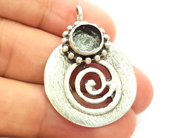 May include: Silver pendant with a round, openwork design featuring a spiral. The pendant has a small, round bezel setting on top.