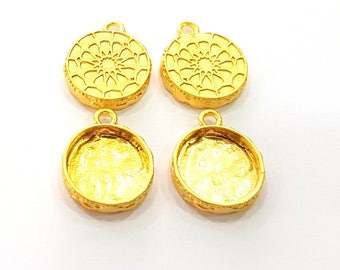 Puede incluir: Cuatro colgantes de metal de color dorado con un diseño circular. Dos colgantes presentan un patrón de mandala detallado, mientras que los otros dos tienen una superficie lisa y lisa.