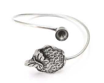 Puede incluir: Pulsera de plata con un diseño de mariposa y hoja. La pulsera está abierta y tiene una pequeña abertura redonda en un extremo.