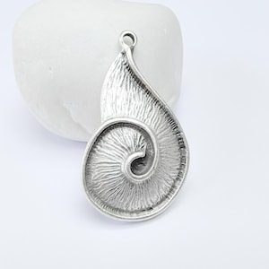 May include: Silver pendant featuring a spiral design. The pendant is teardrop shaped and has a textured finish.