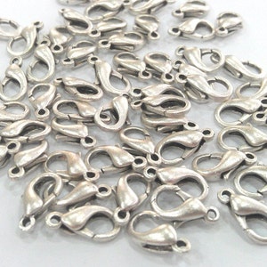 May include: A pile of silver-toned metal lobster claw clasps, commonly used for jewelry making.