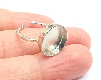 May include: Silver ring with a round bezel setting for a cabochon. The ring is adjustable and has a smooth, polished finish.