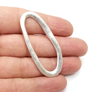 Puede incluir: Un anillo de plata de forma ovalada con una superficie lisa y ligeramente texturizada.