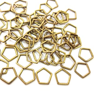 May include: A large pile of gold-colored metal hexagonal jump rings. The rings are all the same size and shape, and they are arranged in a random pattern.