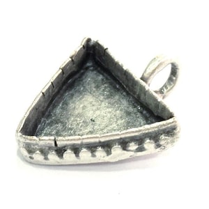 Peut inclure: Pendentif en argent de forme triangulaire avec un bord décoratif et une boucle pour attacher une chaîne.