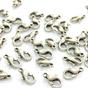 May include: A group of silver-toned lobster clasps, a type of jewellery finding used for attaching chains or cords to jewellery pieces.
