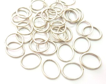 May include: A pile of silver oval jump rings, a type of jewellery finding used for connecting chains, cords, and other jewellery components.