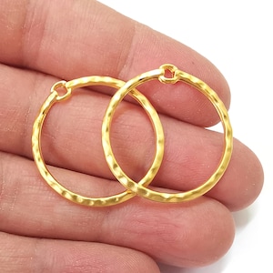 May include: Two gold-toned hammered metal hoops with a small opening at the top. The hoops are about 2 inches in diameter.