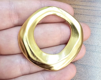 Puede incluir: Un anillo de metal de color dorado con una forma irregular y orgánica. El anillo es grueso y tiene un acabado liso y pulido.
