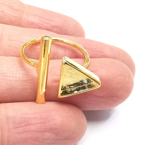 May include: Gold ring with a geometric design. The ring features a thin gold band with a vertical bar and a triangular shape.