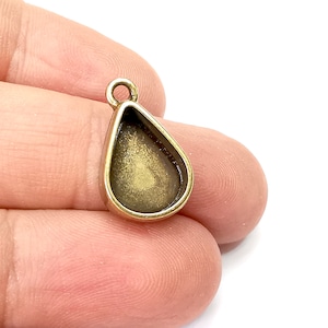 May include: A gold-toned metal pendant with a teardrop-shaped bezel for setting a stone or resin. The pendant has a loop at the top for attaching to a chain or cord.