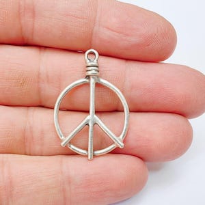 May include: Silver peace sign charm pendant. The charm is a simple, wire-like design of a peace sign.