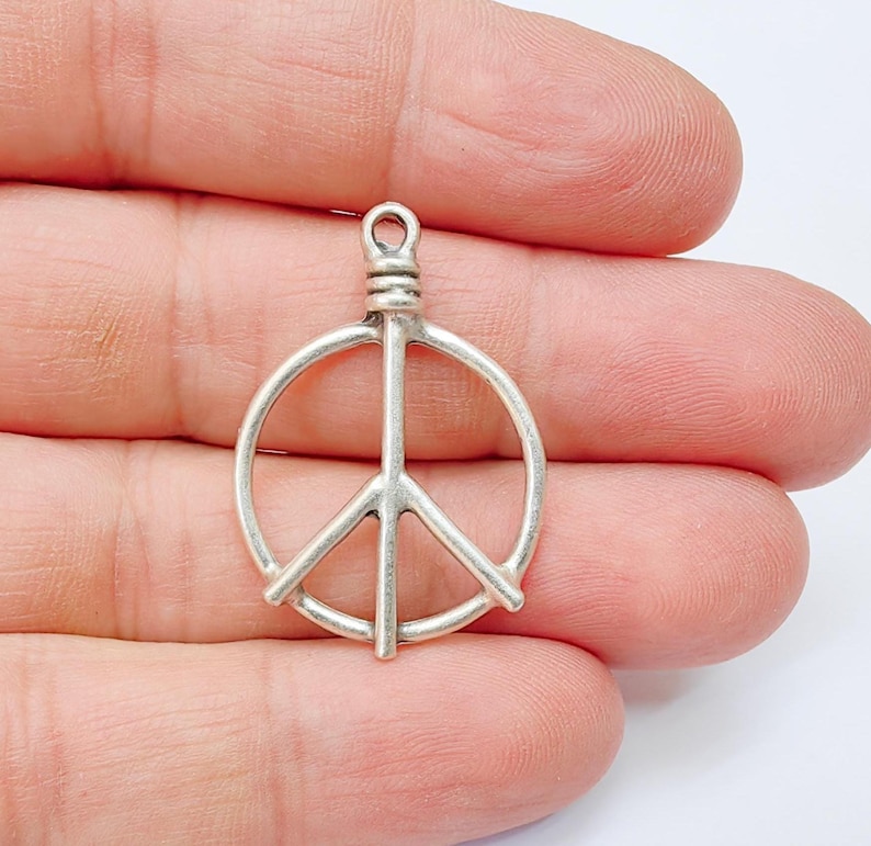 May include: Silver peace sign charm pendant. The charm is a simple, wire-like design of a peace sign.