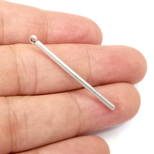 Può includere: Una barra di metallo argentata con un anello nella parte superiore. La barra è lunga circa 5 cm.