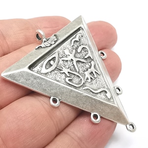 Può includere: Ciondolo triangolare in argento con un occhio e altri simboli in rilievo sulla superficie. Il ciondolo ha cinque anelli di salto per attaccarlo a una catena o un cordino.