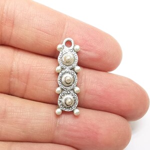 Puede incluir: Encanto de plata con un diseño vertical de cuatro elementos circulares, abalorios y texturados.