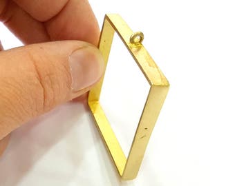 May include: A gold-coloured metal frame with a loop at the top. The frame is square shaped and has a smooth, polished finish.