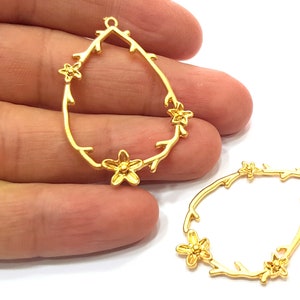 May include: Two gold-tone metal earring blanks in the shape of a teardrop with a floral design. The blanks have a loop at the top for attaching earring wires.
