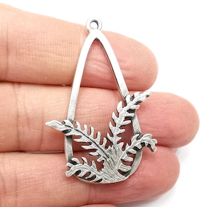 May include: Silver pendant in the shape of a teardrop with a fern design.