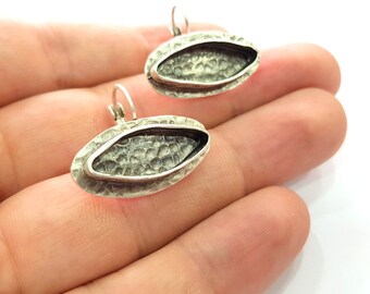 May include: A pair of silver oval earrings with a textured surface and a hollow center.