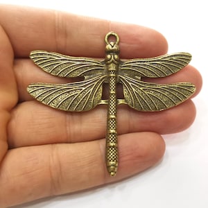 Op de afbeelding: Een bronzen libel charm met gedetailleerde vleugels en een textuur lichaam. De charm heeft een lus aan de bovenkant om te bevestigen aan sieraden of andere knutselwerk.