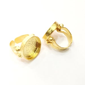 May include: Two gold-toned adjustable rings with round bezels. The bezels are smooth and have a hammered texture. The rings are open at the back and have a decorative design.