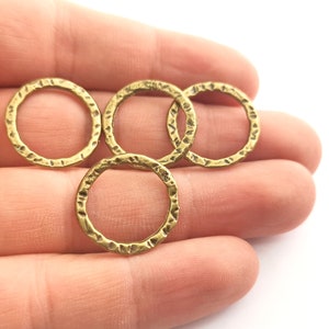Op de afbeelding: Vier gouden metalen ringen met een gehamerde textuur. De ringen hebben een diameter van ongeveer 2,5 cm.