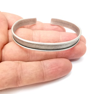 Può includere: Un braccialetto rigido in argento con una fascia larga e piatta e una finitura leggermente testurizzata.