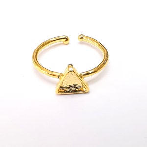May include: A gold adjustable ring with a triangular shaped top.