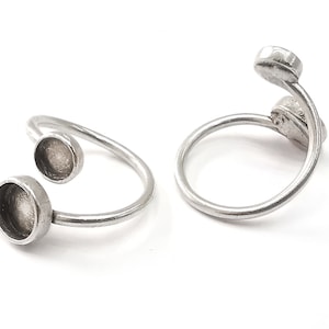 Puede incluir: Dos anillos de plata con engastes redondos y abiertos. Los anillos están diseñados para llevarse en el dedo con los engastes hacia arriba.