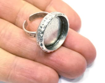 May include: Silver ring with a round, textured bezel setting. The bezel is designed to hold a cabochon or other flat-backed stone.