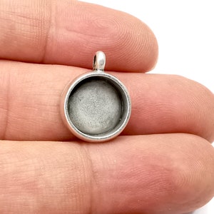 Peut inclure: Pendentif en argent avec un cabochon rond en verre transparent. Le pendentif est conçu pour ajouter une image ou un design personnalisé.