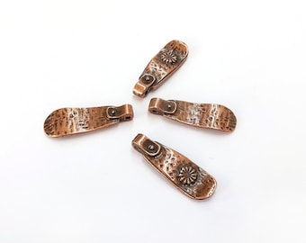 May include: Four antique copper-toned metal charms with a hammered texture and a decorative floral design. Each charm has a loop for attaching to a necklace, bracelet, or other jewelry.