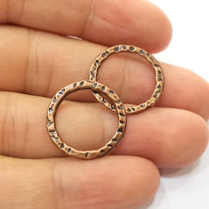 May include: Two hammered copper jump rings, each with a circular shape and a textured surface.