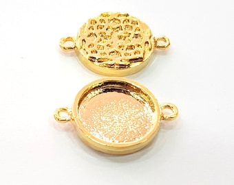 Puede incluir: Dos colgantes redondos de metal dorado con un bucle a cada lado. El colgante superior tiene un patrón decorativo en la parte delantera. El colgante inferior es liso.