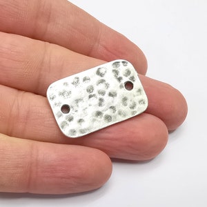 Può includere: Etichetta rettangolare in argento con una texture martellata e due fori per attaccare un cordino o una catena.