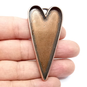 May include: A copper-colored heart-shaped pendant with a pointed bottom. The pendant is made of metal and has a smooth, shiny finish.